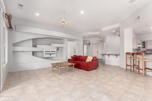 living room featuring ceiling fan with notable chandelier, built in features, visible vents, and recessed lighting