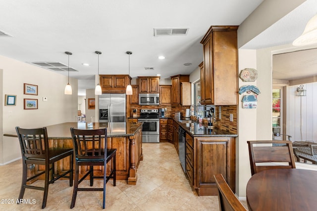 kitchen featuring stainless steel appliances, a kitchen island, a sink, visible vents, and decorative backsplash