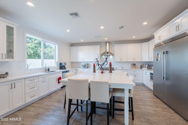 3834 E Clarendon Ave, Phoenix, AZ 85018 - kitchen with stainless steel appliances, wall chimney exhaust hood, a kitchen island, white cabinetry, and recessed lighting