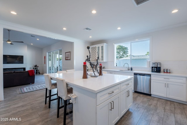 3834 E Clarendon Ave, Phoenix, AZ 85018 - kitchen with stainless steel dishwasher, a sink, a breakfast bar area, light wood-style floors, and crown molding