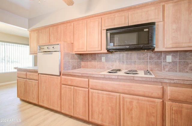 kitchen featuring tile countertops, white appliances, light hardwood / wood-style floors, and backsplash