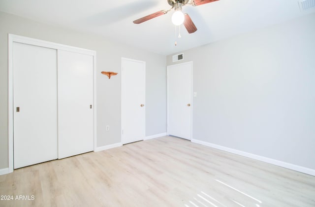 unfurnished bedroom featuring ceiling fan, light hardwood / wood-style floors, and a closet