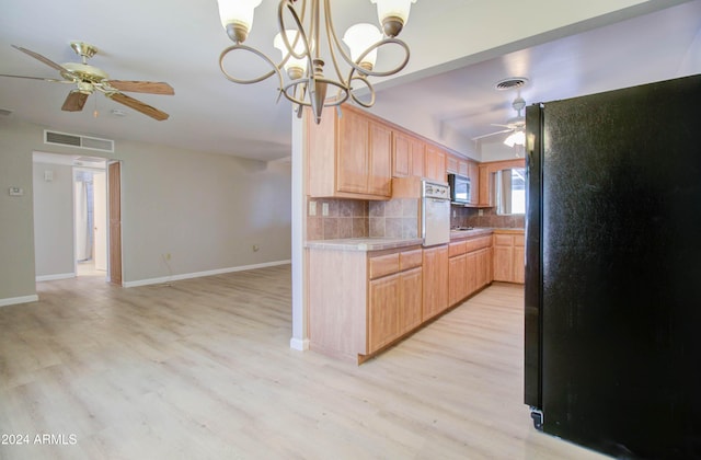 kitchen with black refrigerator, decorative backsplash, light brown cabinets, a chandelier, and light hardwood / wood-style floors