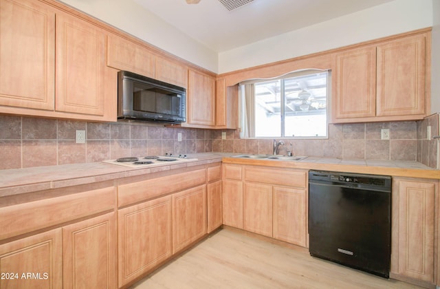 kitchen featuring sink, light brown cabinets, light hardwood / wood-style flooring, tile countertops, and black appliances