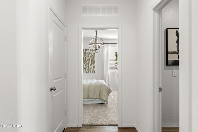 18348 W Gray Fox Trl, Wittmann, AZ 85361 - hallway featuring dark wood-style flooring, visible vents, baseboards, and an inviting chandelier