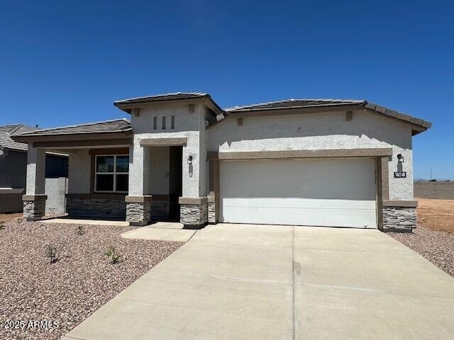 18348 W Gray Fox Trl, Wittmann, AZ 85361 - prairie-style house featuring driveway, stone siding, a garage, and stucco siding