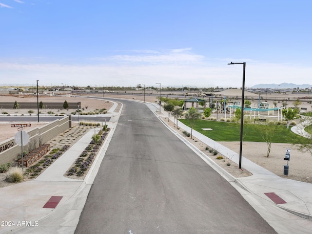 18348 W Gray Fox Trl, Wittmann, AZ 85361 - view of road with sidewalks, street lights, a mountain view, and curbs