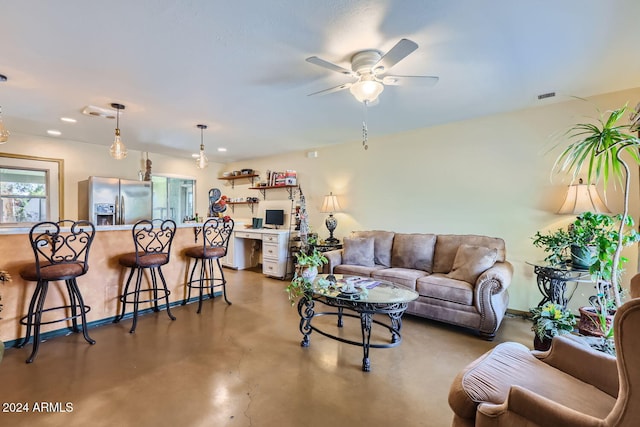 living room with ceiling fan, built in desk, and concrete floors