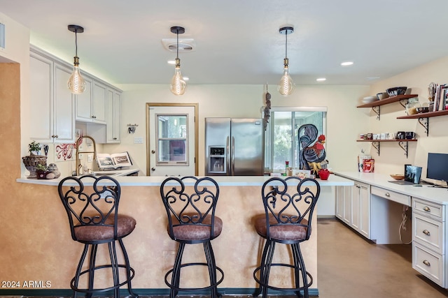 kitchen with a breakfast bar, stainless steel refrigerator with ice dispenser, pendant lighting, and white cabinetry