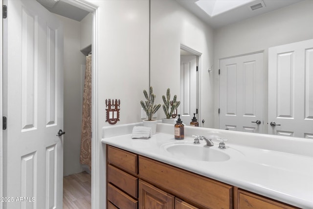 bathroom with hardwood / wood-style flooring, a skylight, and vanity