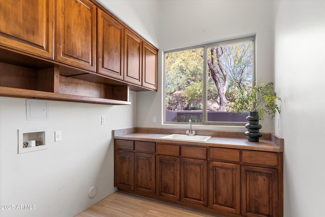 clothes washing area featuring cabinets, sink, light hardwood / wood-style floors, and hookup for a washing machine