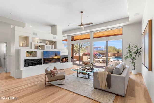 living room with a multi sided fireplace, built in shelves, and light wood-type flooring