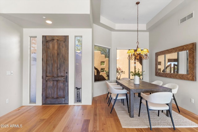 dining area with a tray ceiling, hardwood / wood-style floors, and a chandelier