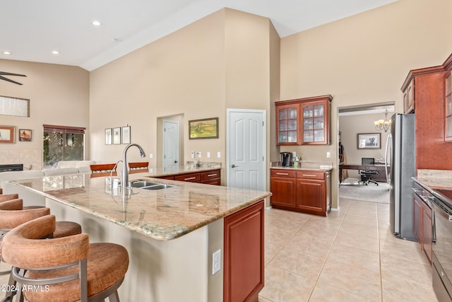 kitchen with stainless steel refrigerator, a kitchen island with sink, sink, and a breakfast bar