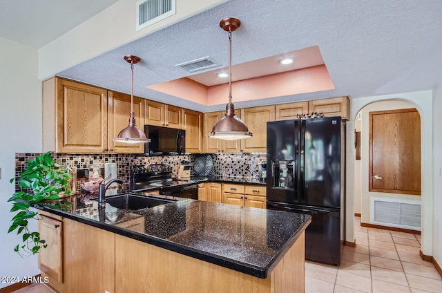 kitchen with visible vents, a peninsula, a tray ceiling, black appliances, and a sink