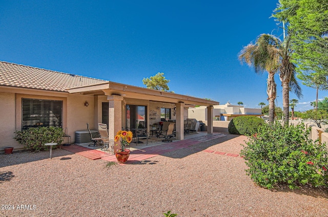 rear view of house with a tiled roof, a patio area, fence, and stucco siding