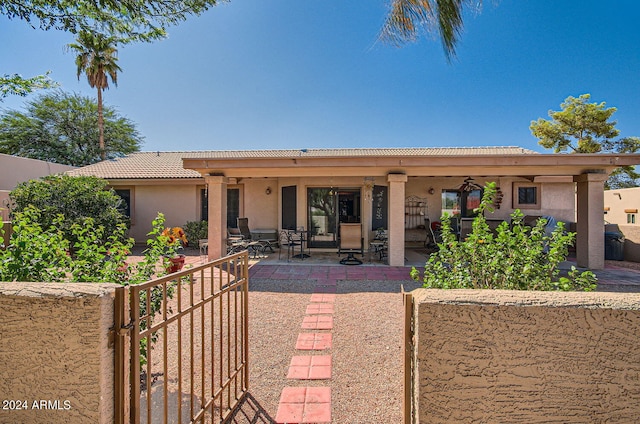 view of front of property with a tiled roof, a patio, fence, and stucco siding