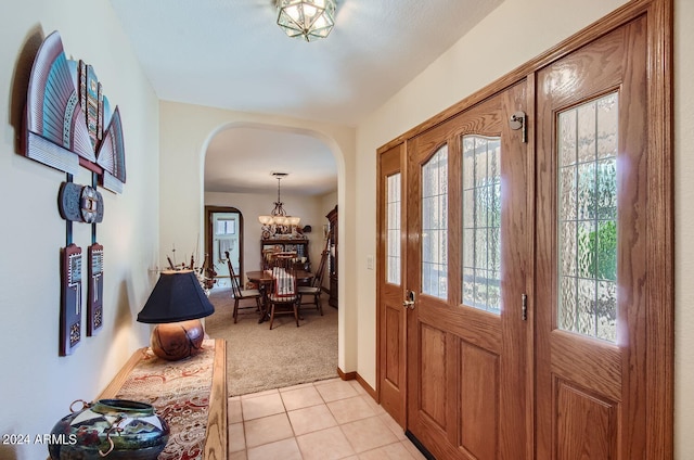 foyer entrance with light colored carpet, arched walkways, and a healthy amount of sunlight