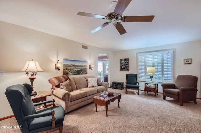 carpeted living area with a ceiling fan, arched walkways, visible vents, and baseboards