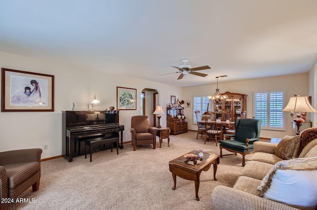 living room featuring arched walkways, light colored carpet, baseboards, and ceiling fan with notable chandelier