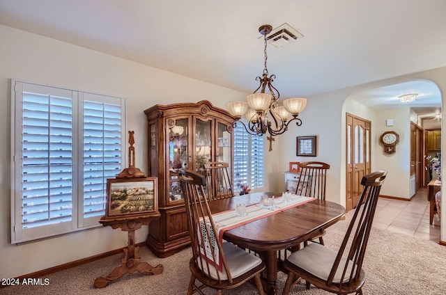 dining room featuring a notable chandelier, arched walkways, a wealth of natural light, and light colored carpet