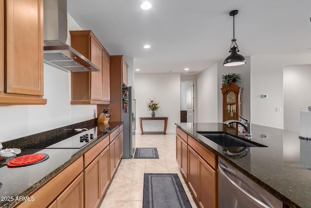 kitchen with wall chimney range hood, sink, dark stone countertops, decorative light fixtures, and stainless steel appliances