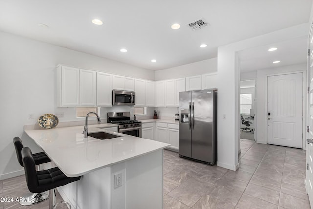 kitchen featuring kitchen peninsula, stainless steel appliances, white cabinetry, and sink