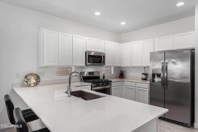 kitchen featuring kitchen peninsula, stainless steel appliances, white cabinets, and sink