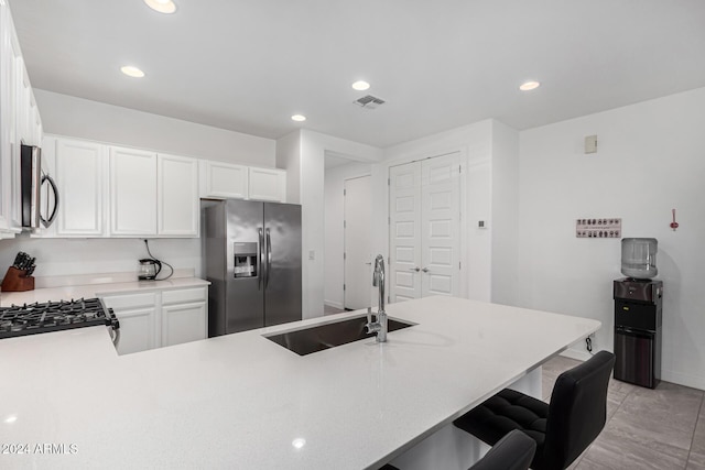 kitchen with sink, kitchen peninsula, a kitchen bar, white cabinets, and appliances with stainless steel finishes