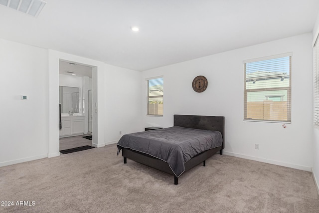 bedroom featuring light carpet and connected bathroom