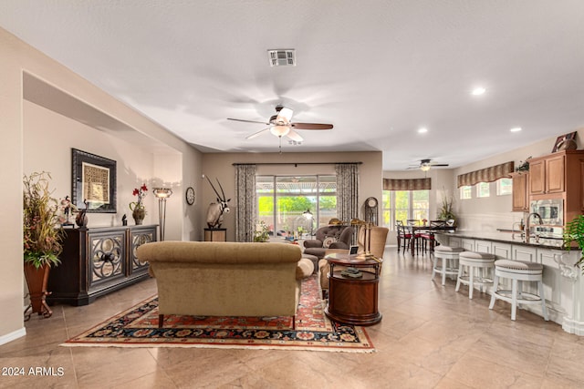 living area featuring baseboards, visible vents, a ceiling fan, and recessed lighting