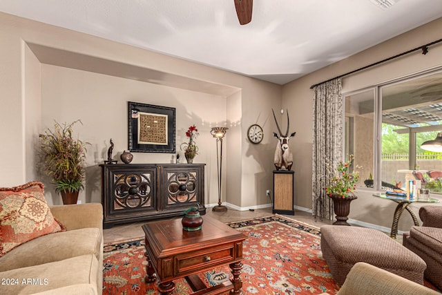 living area featuring baseboards, a ceiling fan, and tile patterned floors