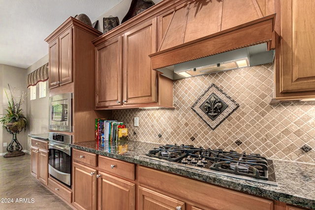 kitchen with appliances with stainless steel finishes, dark stone counters, and brown cabinets