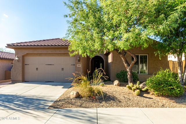 view of front of property featuring driveway, a tiled roof, an attached garage, and stucco siding