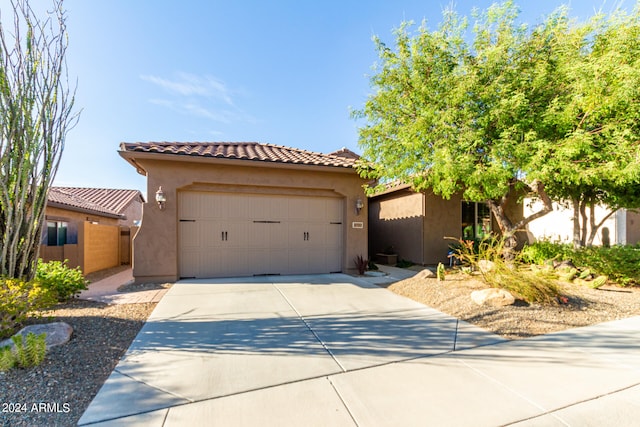 view of front of house featuring a garage, driveway, a tile roof, and stucco siding