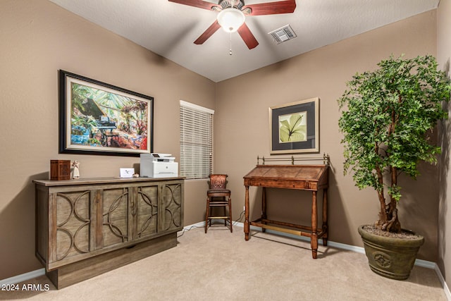 living area featuring ceiling fan, visible vents, baseboards, and light colored carpet