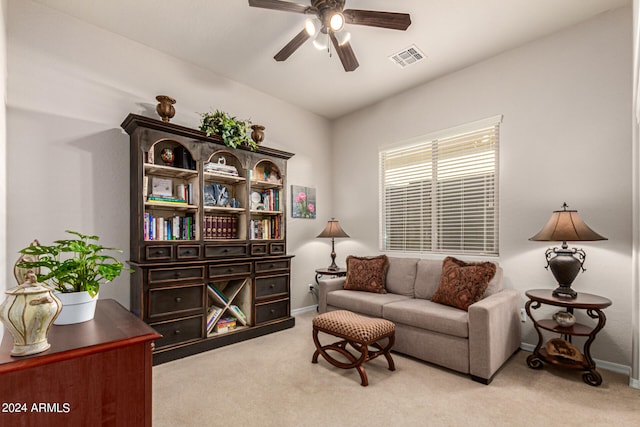 living area with baseboards, a ceiling fan, visible vents, and light colored carpet