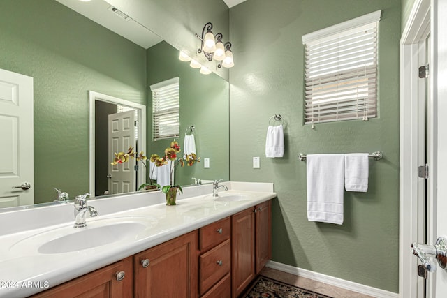 bathroom with double vanity, baseboards, visible vents, and a sink