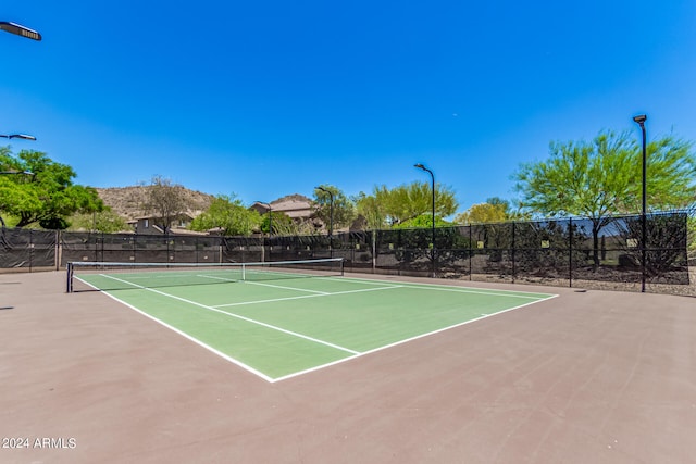 view of tennis court featuring community basketball court and fence