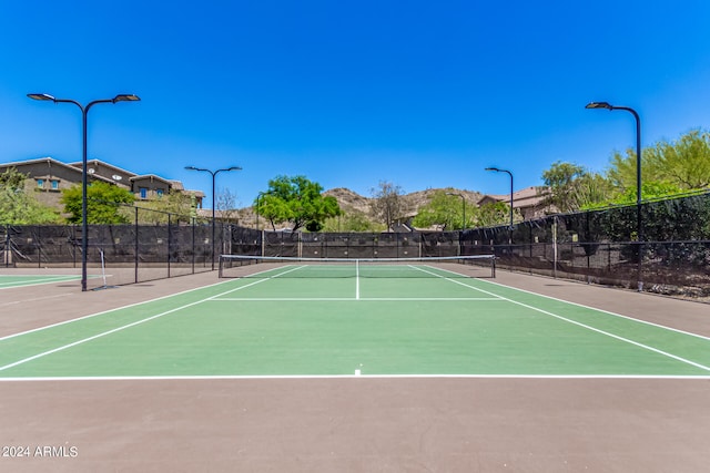 view of tennis court featuring community basketball court and fence