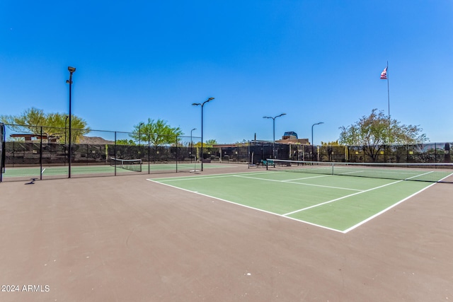 view of tennis court with community basketball court and fence