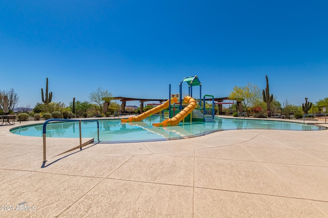 view of pool featuring playground community, a water slide, and a water play area