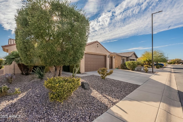 view of front of property with an attached garage, stucco siding, concrete driveway, and a tiled roof