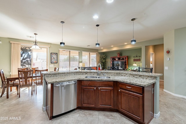 kitchen with decorative light fixtures, dishwasher, a sink, and a center island with sink