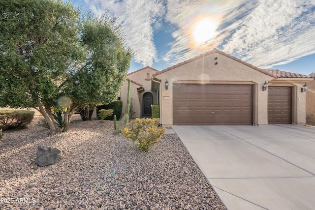 view of front of house featuring a garage, driveway, a tile roof, and stucco siding