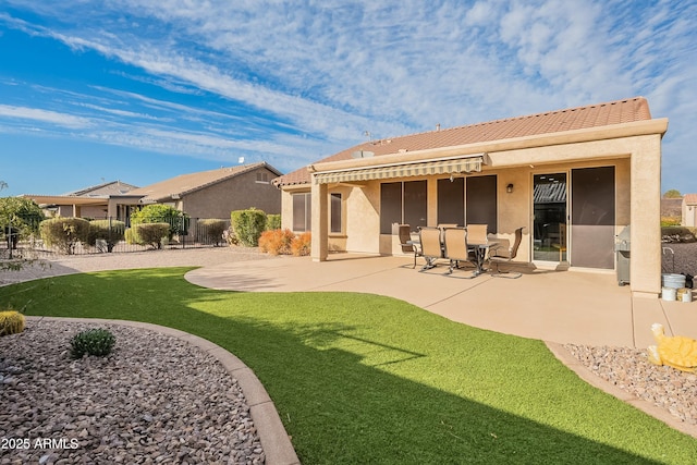 back of property featuring a patio, fence, a tile roof, a yard, and stucco siding