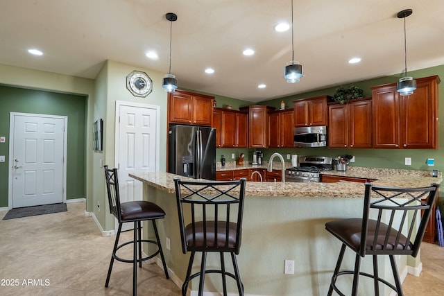 kitchen featuring an island with sink, a kitchen bar, appliances with stainless steel finishes, and decorative light fixtures