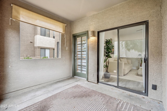 view of exterior entry with a balcony and stucco siding