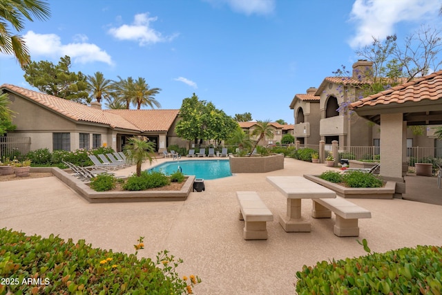 community pool with a patio and fence