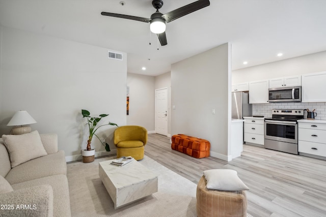 living area with light wood-type flooring, ceiling fan, baseboards, and recessed lighting